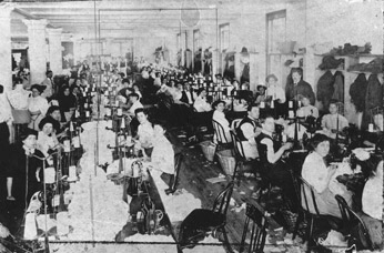 Operators sitting at sewing machines in a factory similar to the Triangle Factory